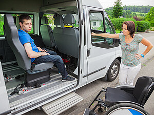 Kind im Rollstuhl wird von einem Großraumtaxi abgeholt Kind im Rollstuhl wird von einem Großraumtaxi abgeholt